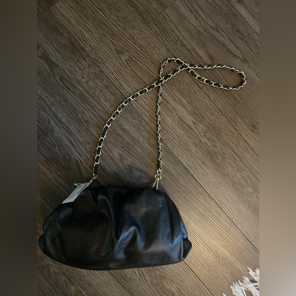Simon’s black leather clutch purse with gold and leather removable strap
